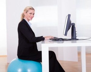 Frau auf Gymnastikball vor PC